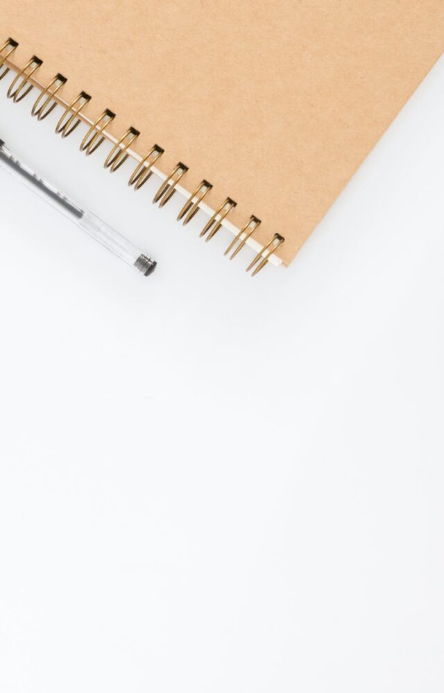 black ball point pen with brown spiral notebook
